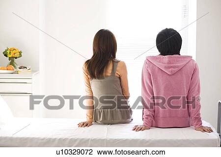 Stock Image - Couple sitting on a hospital bed. Fotosearch