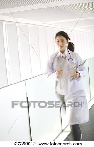 Stock Image - Doctor running with chart through hallway. Fotosearch