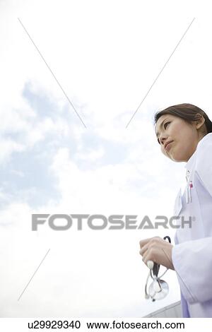 Stock Image - Doctor standing outside holding stethoscope. Fotosearch