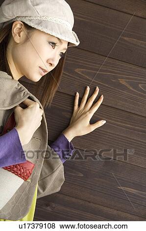 Stock Photo - Fashionable woman against brown wooden wall. Fotosearch