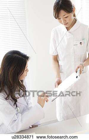 Female doctor discussing a medical chart with a nurse View Large Photo Image Stock Image - Female doctor discussing a medical chart with a nurse. Fotosearch