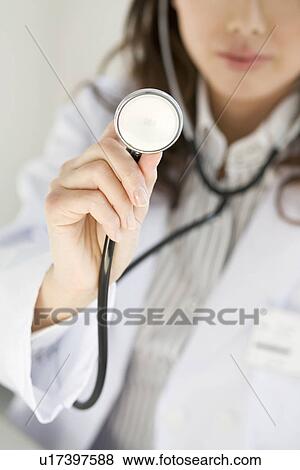 Stock Photo - Female doctor holding out a stethoscope. Fotosearch