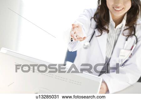 Stock Image - Female doctor holding out her hand. Fotosearch