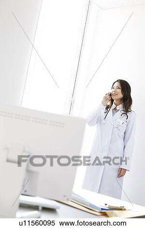 Stock Photography - Female doctor talking on a mobile phone. Fotosearch