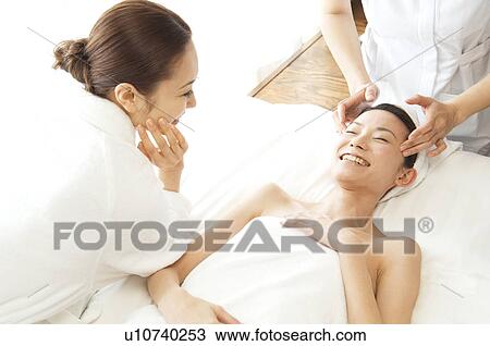 Stock Image - Friends take turns receiving massages. Fotosearch