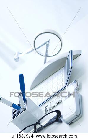 Picture - Glasses, pens, calculator, cellphone and wristwatch on desk. Fotosearch
