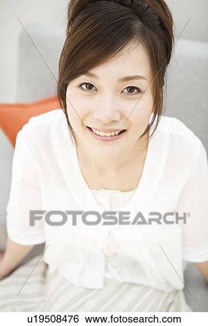 Happy woman sitting on sofa View Large Photo Image Stock Photograph - Happy woman sitting on sofa. Fotosearch