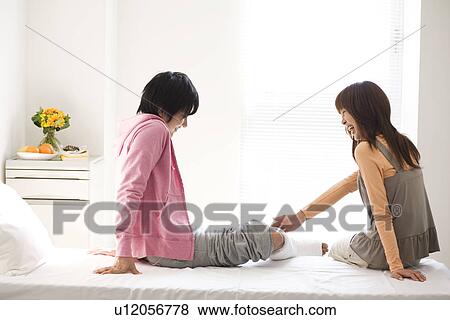 Stock Photo - Her who is touching the boyfriend's broken leg. Fotosearch