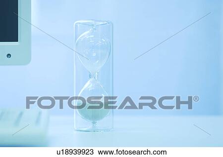 Stock Image - Hourglass next to computer. Fotosearch