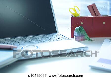 Stock Photograph - Laptop on desk with notebook. Fotosearch
