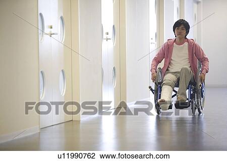 Stock Image - Man with broken leg in a wheelchair. Fotosearch