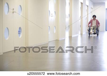 Stock Image - Man with broken leg in a wheelchair. Fotosearch