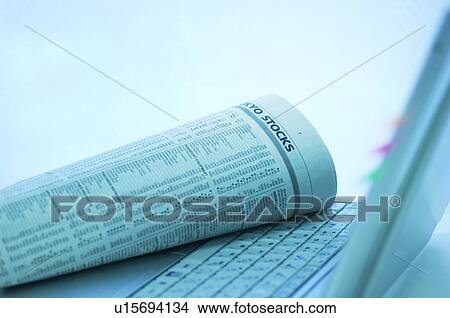 Picture - Newspaper with stock exchange on laptop keyboard. Fotosearch