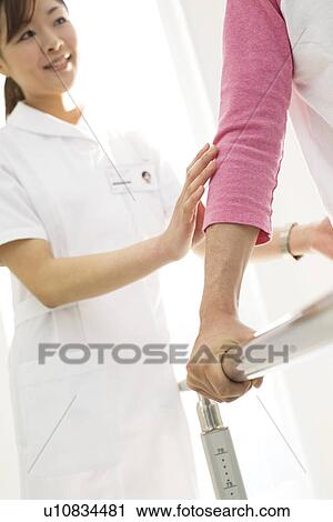 Stock Image - Nurse assisting a patient with rehabilitation. Fotosearch