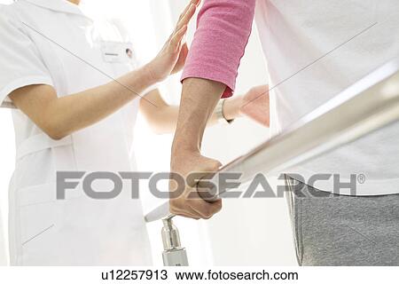 Nurse assisting a patient with rehabilitation View Large Photo Image Stock Image - Nurse assisting a patient with rehabilitation. Fotosearch