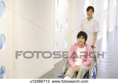 Nurse pushing patient in wheelchair along a corridor View Large Photo Image Stock Image - Nurse pushing patient in wheelchair along a corridor. Fotosearch