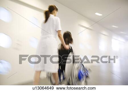 Nurse pushing patient in wheelchair along a corridor View Large Photo Image Stock Photo - Nurse pushing patient in wheelchair along a corridor. Fotosearch