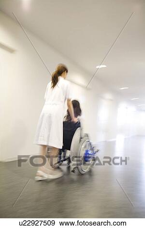 Nurse pushing patient in wheelchair along a corridor View Large Photo Image Stock Photo - Nurse pushing patient in wheelchair along a corridor. Fotosearch