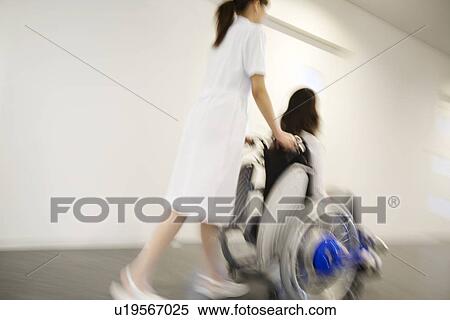 Nurse pushing patient in wheelchair along a corridor View Large Photo Image Stock Photography - Nurse pushing patient in wheelchair along a corridor. Fotosearch