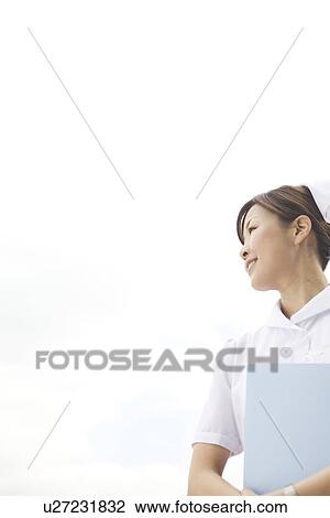 Nurse standing outside holding file View Large Photo Image Stock Image - Nurse standing outside holding file. Fotosearch