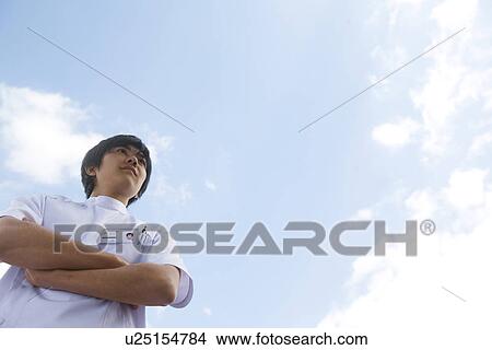 Picture - Nurse standing outside with folded arms. Fotosearch