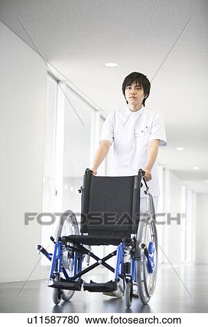 Orderly pushing wheelchair in hospital View Large Photo Image Stock Image - Orderly pushing wheelchair in hospital. Fotosearch