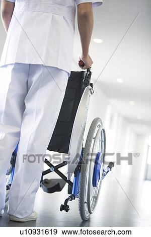 Orderly pushing wheelchair in hospital View Large Photo Image Stock Photo - Orderly pushing wheelchair in hospital. Fotosearch