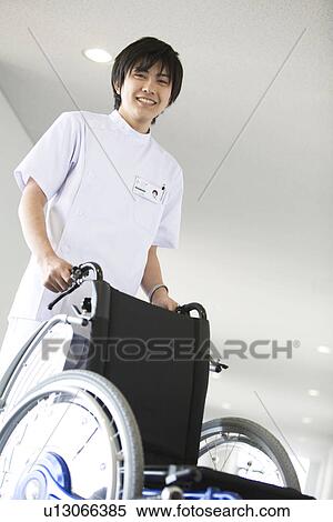 Stock Photography - Orderly pushing wheelchair in hospital. Fotosearch