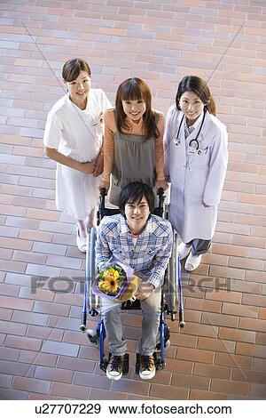 Stock Photo - Patient with his doctor and nurse outside a hospital. Fotosearch