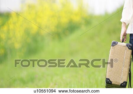 Person walking through field carrying suitcase View Large Photo Image Picture - Person walking through field carrying suitcase. Fotosearch