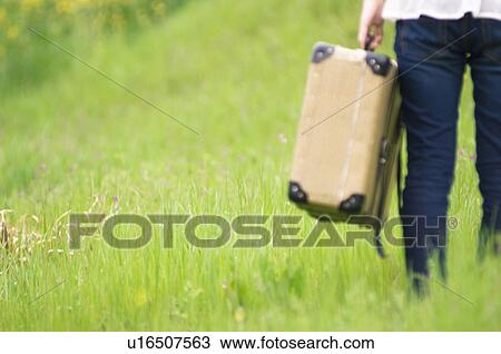 Person walking through field carrying suitcase View Large Photo Image Stock Image - Person walking through field carrying suitcase. Fotosearch