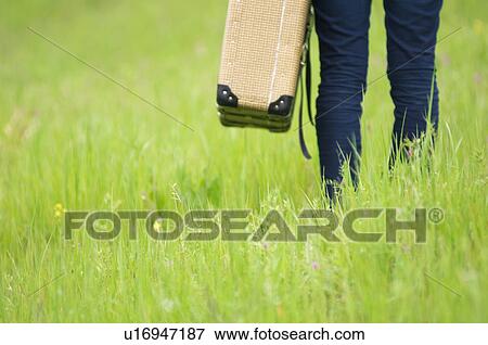 Person walking through field carrying suitcase View Large Photo Image Stock Photo - Person walking through field carrying suitcase. Fotosearch