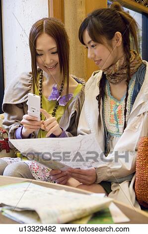 Stock Image - Two friends planning their travels in a hotel lobby. Fotosearch