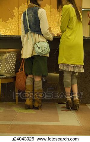 Two women checking into a hotel View Large Photo Image Stock Photograph - Two women checking into a hotel. Fotosearch