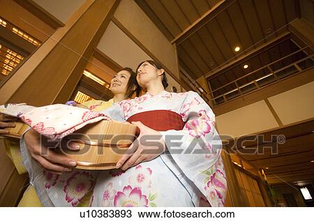 Stock Image - Two women wearing yukata and holding spa products at a health spa. Fotosearch