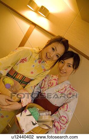 Stock Image - Two women wearing yukata and holding spa products at a health spa. Fotosearch
