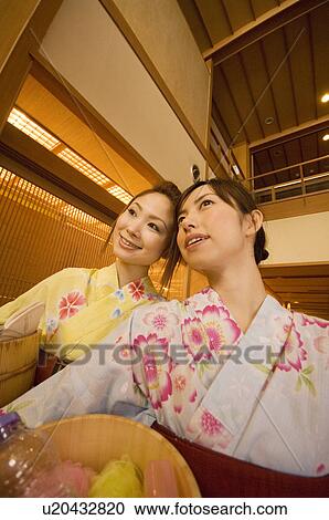 Stock Image - Two women wearing yukata and holding spa products at a health spa. Fotosearch