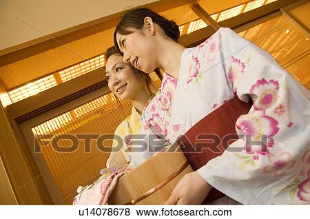 Stock Photo - Two women wearing yukata and holding spa products at a health spa. Fotosearch