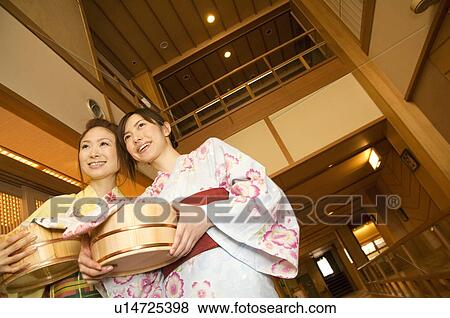 Stock Photo - Two women wearing yukata and holding spa products at a health spa. Fotosearch
