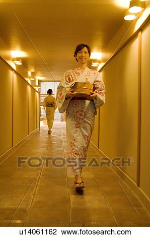 Stock Image - Two women wearing yukata walking through the corridor of a health spa. Fotosearch
