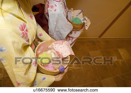 Stock Image - Two women wearing yukata walking through the corridor of a health spa. Fotosearch