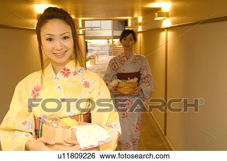 Stock Photograph - Two women wearing yukata walking through the corridor of a health spa. Fotosearch