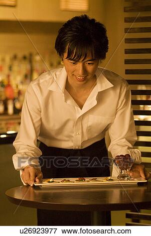 Stock Photo - Waiter carrying a plate of food to a table. Fotosearch