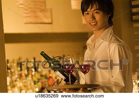 Stock Photo - Waiter carrying wine to a table. Fotosearch