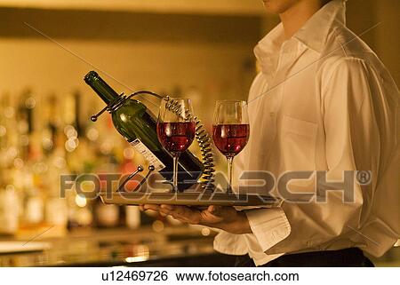 Stock Photograph - Waiter carrying wine to a table. Fotosearch