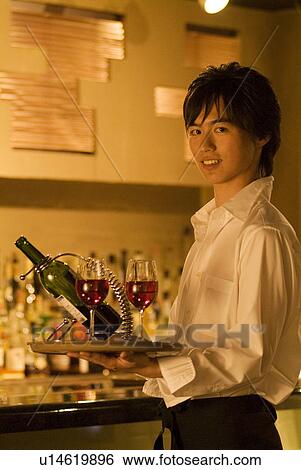 Stock Photograph - Waiter carrying wine to a table. Fotosearch