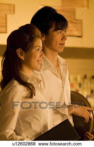 Stock Photo - Waiters holding a menu and a tray. Fotosearch