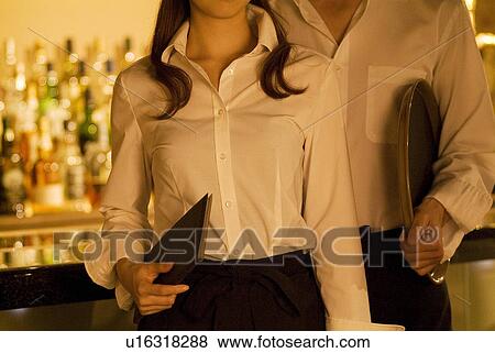 Stock Photo - Waiters holding a menu and a tray. Fotosearch