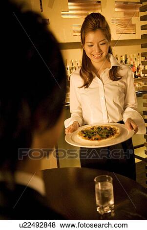 Waitress bringing a pizza to a table View Large Photo Image Stock Photo - Waitress bringing a pizza to a table. Fotosearch