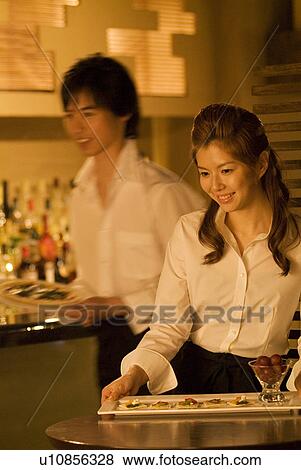 Stock Photo - Waitress carrying a plate of food to a table. Fotosearch